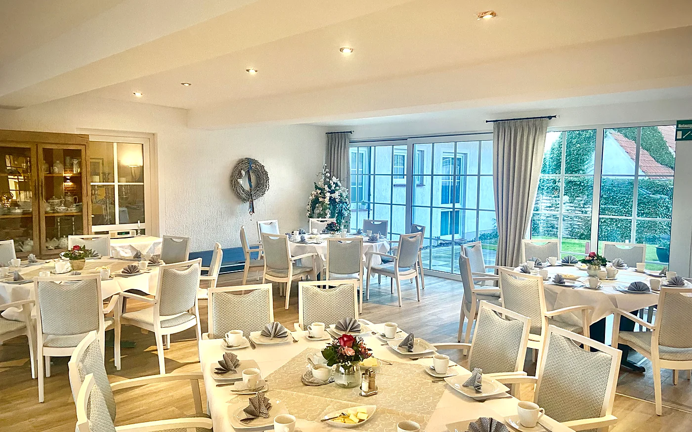 Bright breakfast room at Hotel Rohdenburg with laid tables and a view of the garden